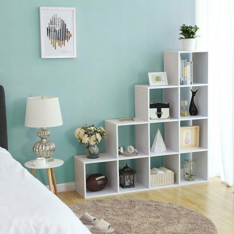 Regał schodkowy w aranżacji sypialnianej, uzupełniony przyborami codziennego użytku.