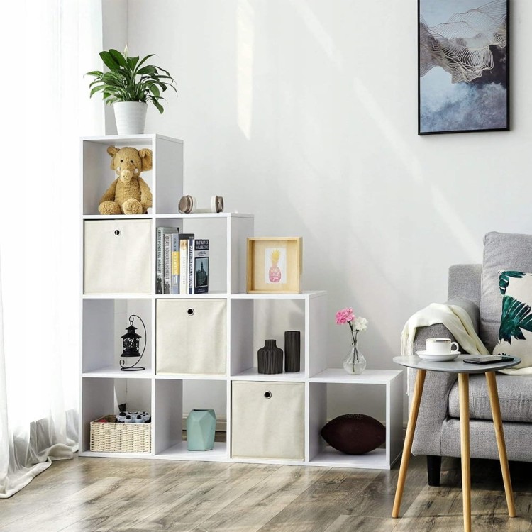 Półka dekoracyjna ustawiona w sypialni obok kanapy, wypełniona książkami.