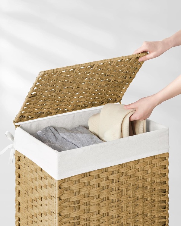 Osoba wkładająca ubrania do wiklinowego kosza na pranie.