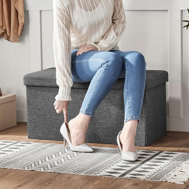 Kobieta ubierająca buty która siedzi na szarej pufie.