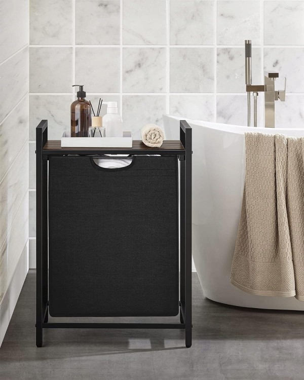 Kosz na pranie Vasagle 65 l z półką w stylu loft ustawiony przy wannie