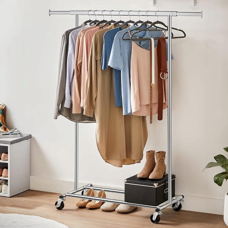 Mobilny stojak z zawieszonymi ubraniami na drążku.