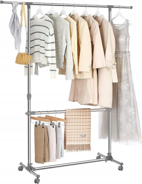 Metalowy wieszak stojący z wyeksponowanymi ubraniami oraz dodatkami.
