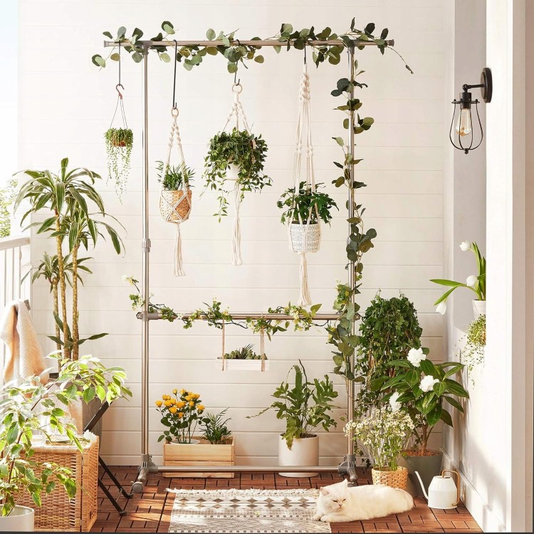 Wieszak stojący w salonie który służy jako stojak na rośliny pokojowe