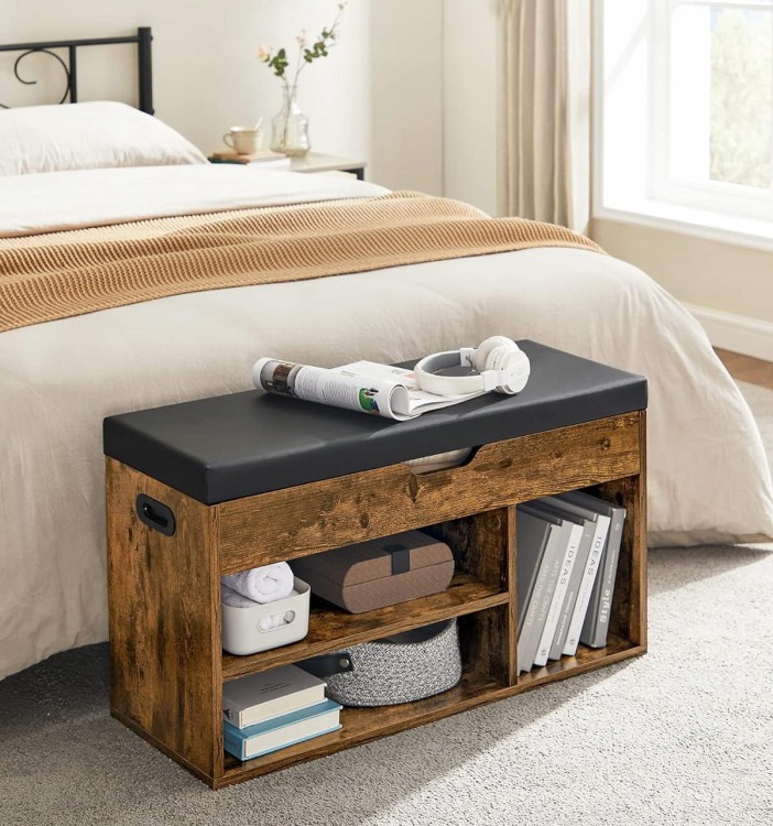 Skrzynia z pufą, wyeksponowana na tle łóżka z kilkoma akcesoriami.