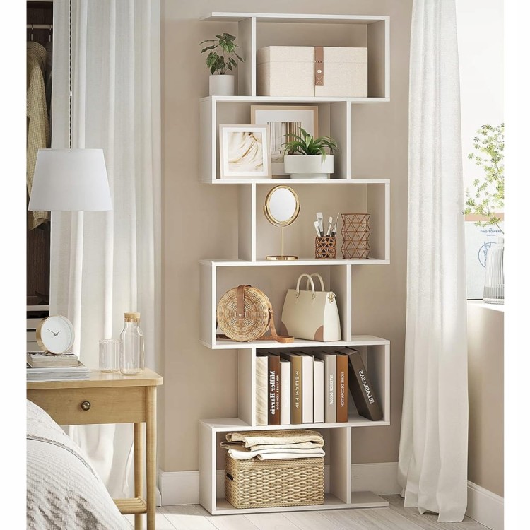 Regał stojący ustawiony w sypialni, komponujący się z licznymi dodatkami.